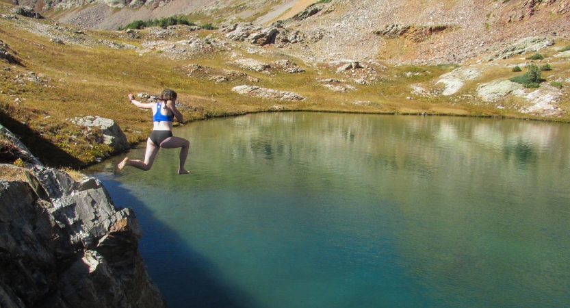 A person jumps off a rock into a body of water.